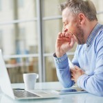 Tired man yawning at workplace in office